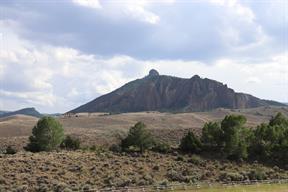 Sheer stone cliffs loomed behind the houses down on the sagebrush hills